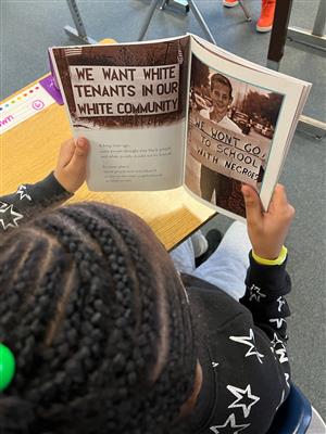 Photo shows a girl reading a book about Ruby Bridges. 
